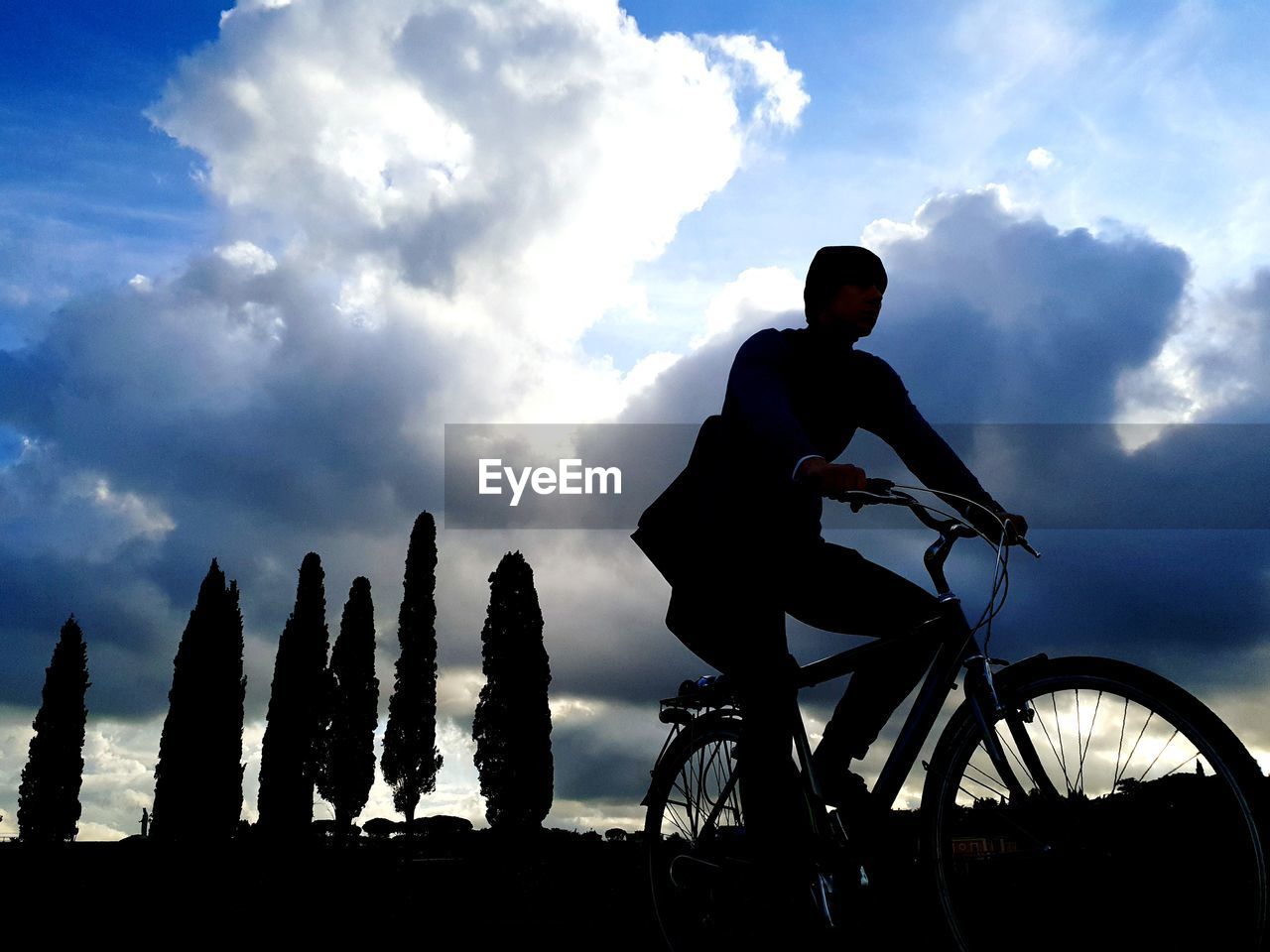 MAN RIDING BICYCLE AGAINST SKY