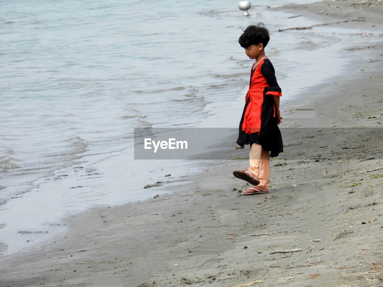 FULL LENGTH OF BOY WALKING ON BEACH