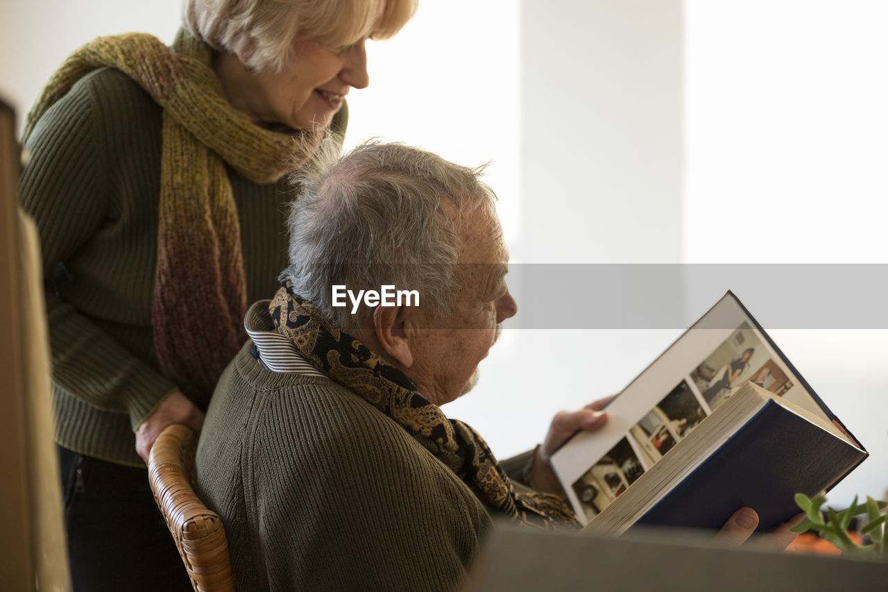 Senior couple looking at photo album surrounded by cardboard boxes in an empty room