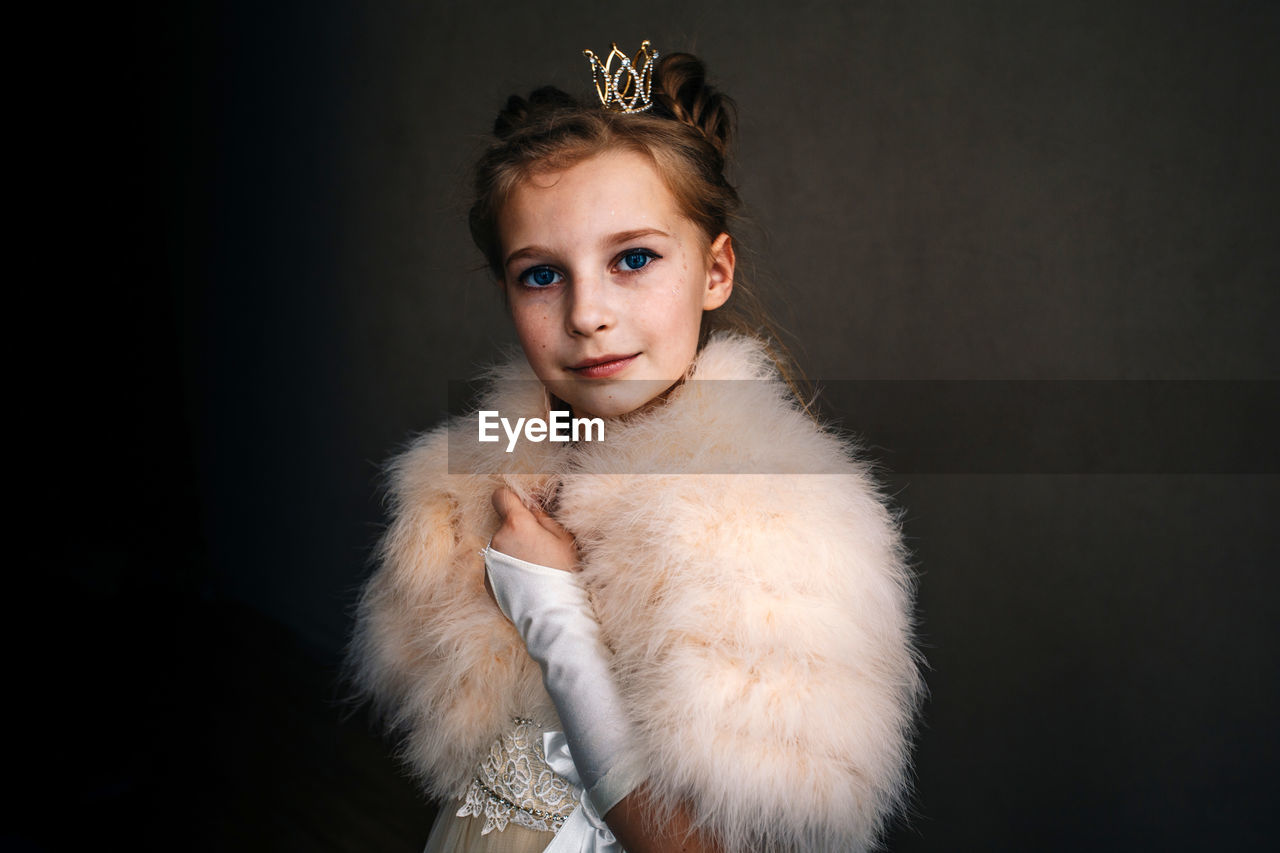 Portrait of smiling girl in princess costume against black background