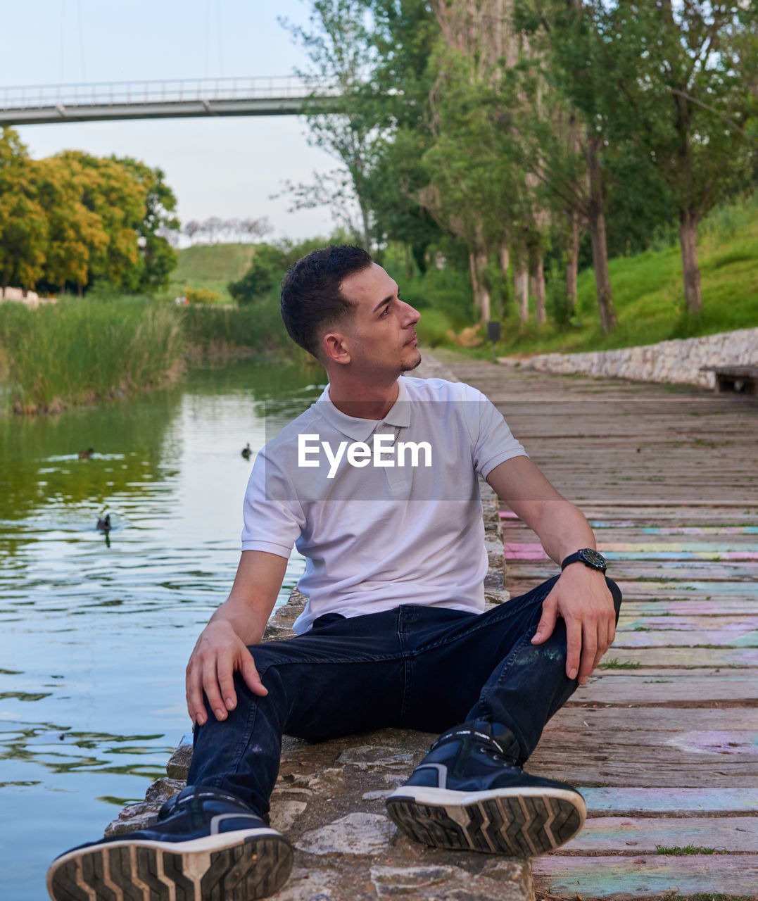 Portrait of young man sitting at lakeshore