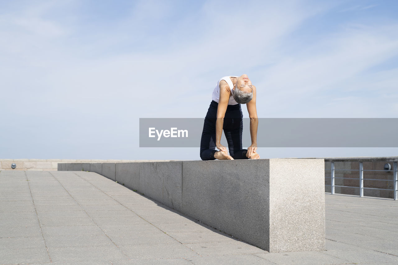 Woman practicing yoga on pier