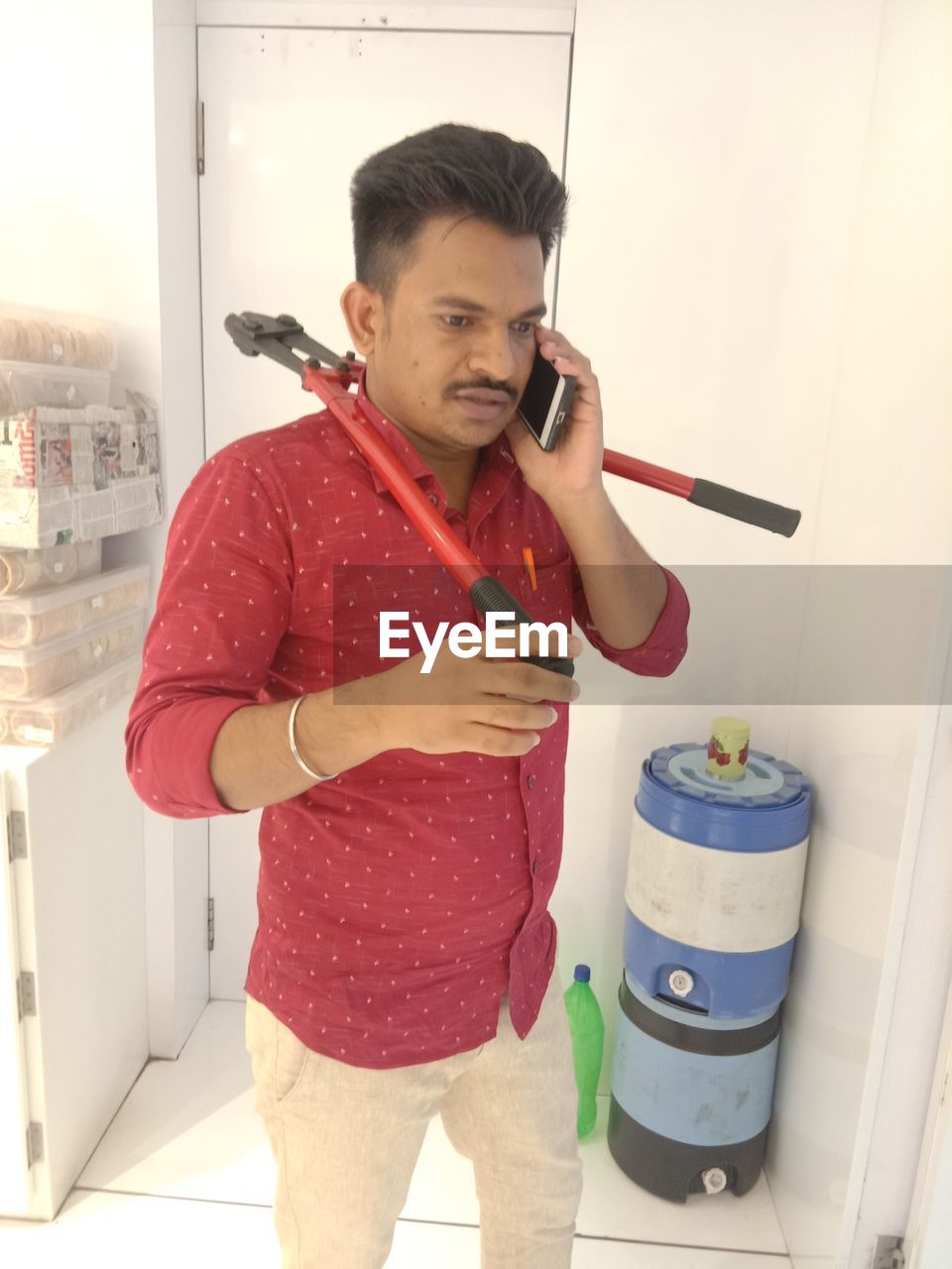 Young man talking on mobile phone while standing against wall