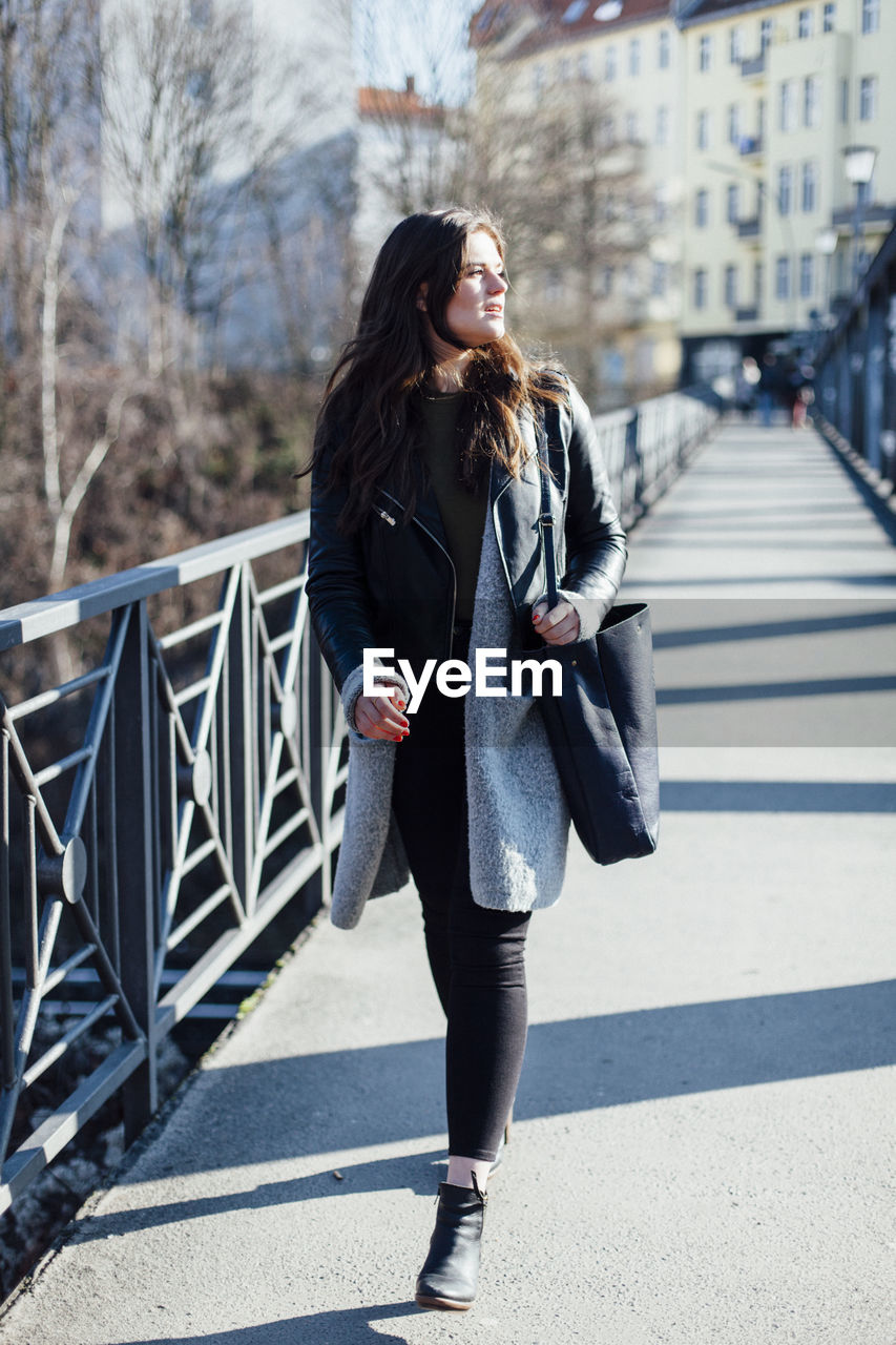 Beautiful young woman walking on footbridge during sunny day