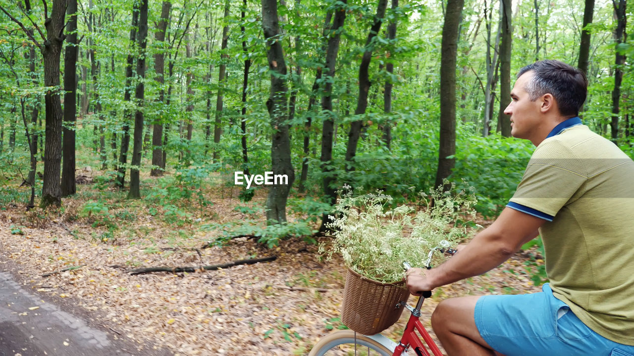 A man riding a bicycle in the forest, in the summer