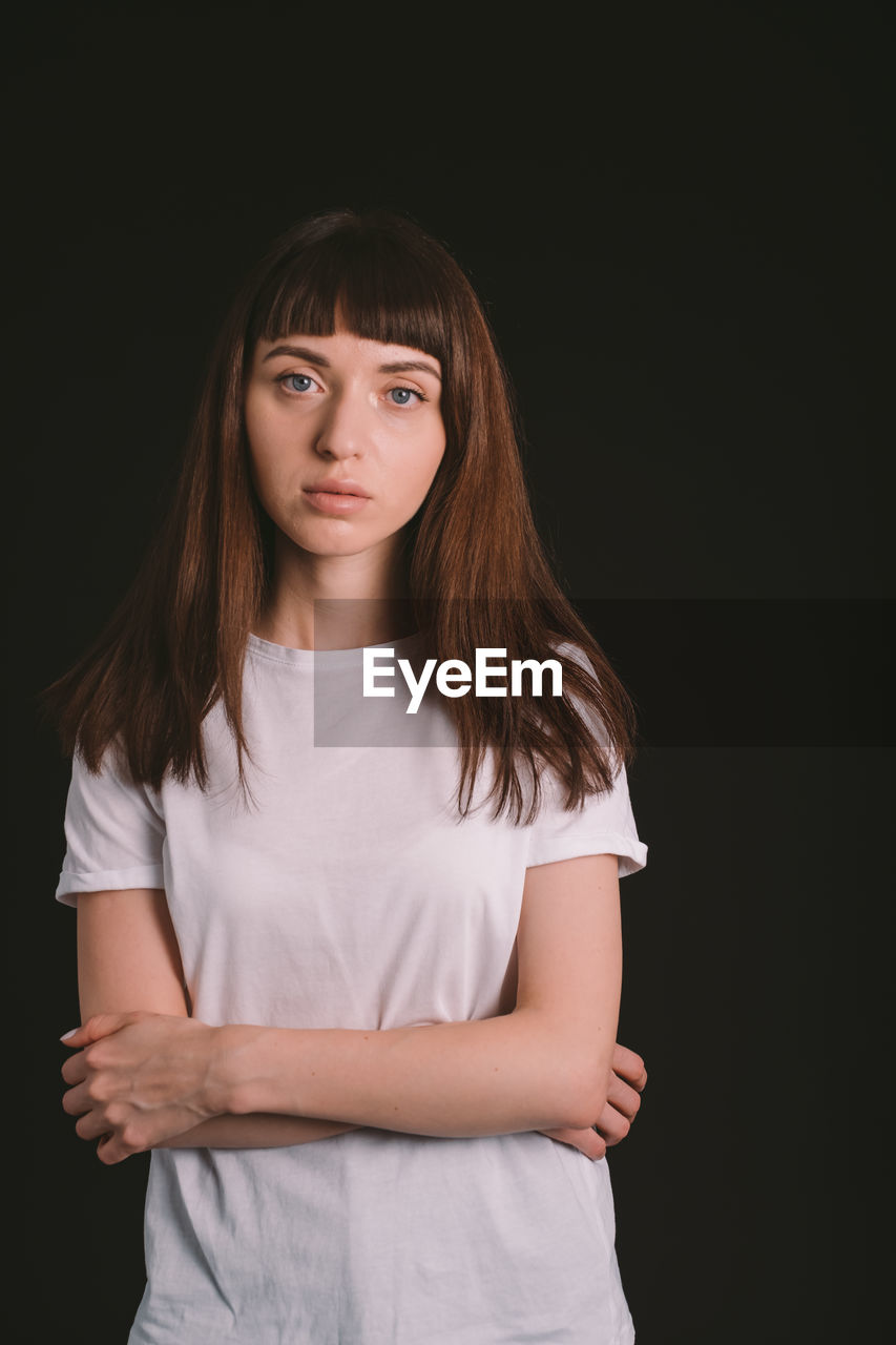 PORTRAIT OF YOUNG WOMAN AGAINST BLACK BACKGROUND