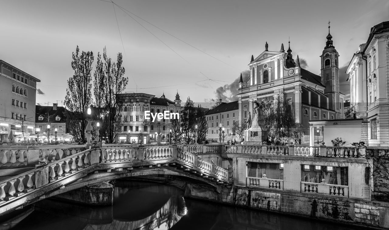 BRIDGE OVER CANAL AMIDST BUILDINGS IN CITY