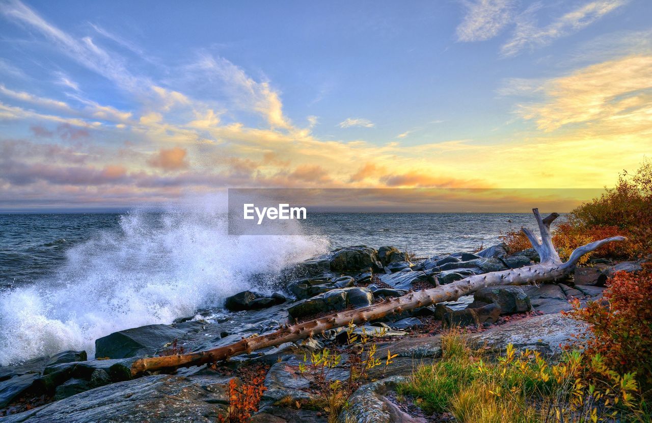 Waves breaking on rocks against the sky