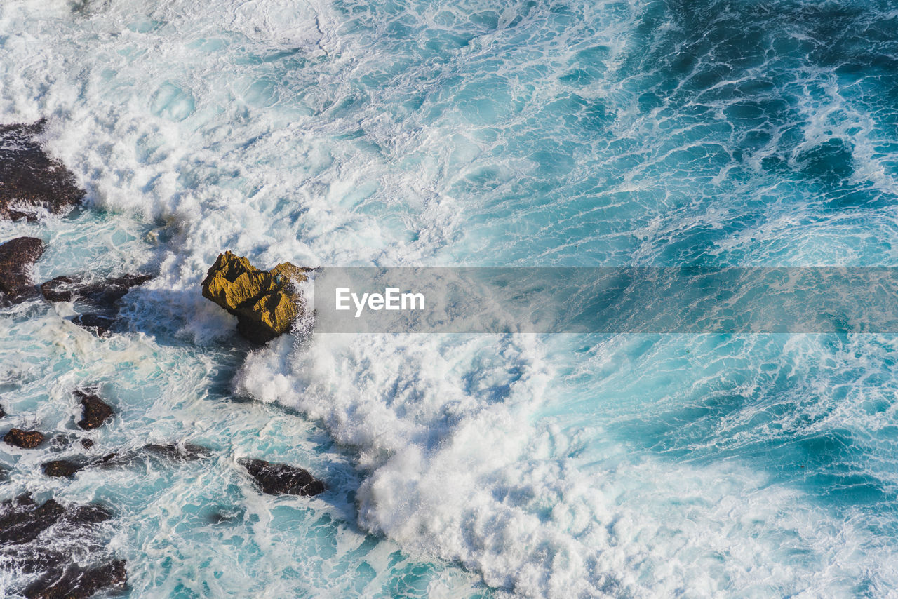 High angle view of wave splashing at rocky shore