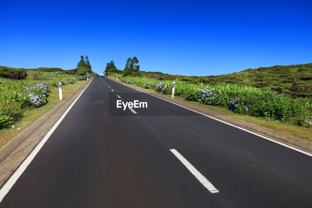 Road amidst landscape against clear blue sky