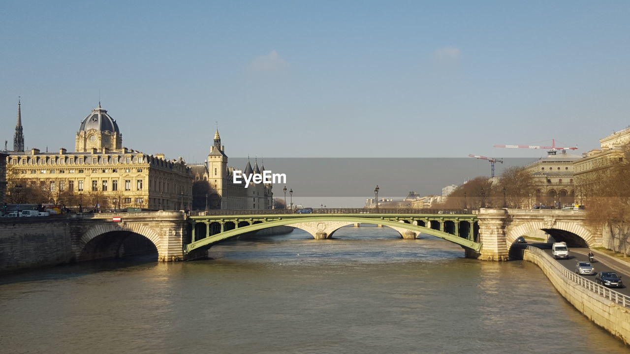 Bridge over river in city against sky