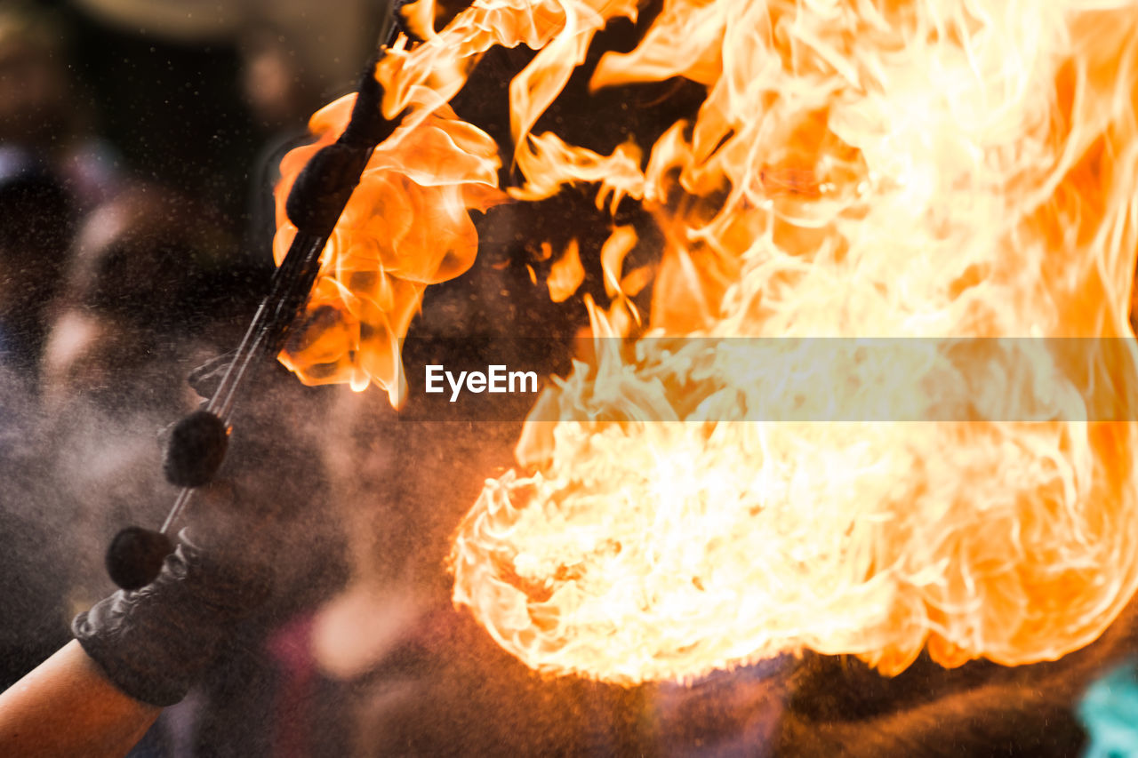 Close-up of hand holding fire against blurred background