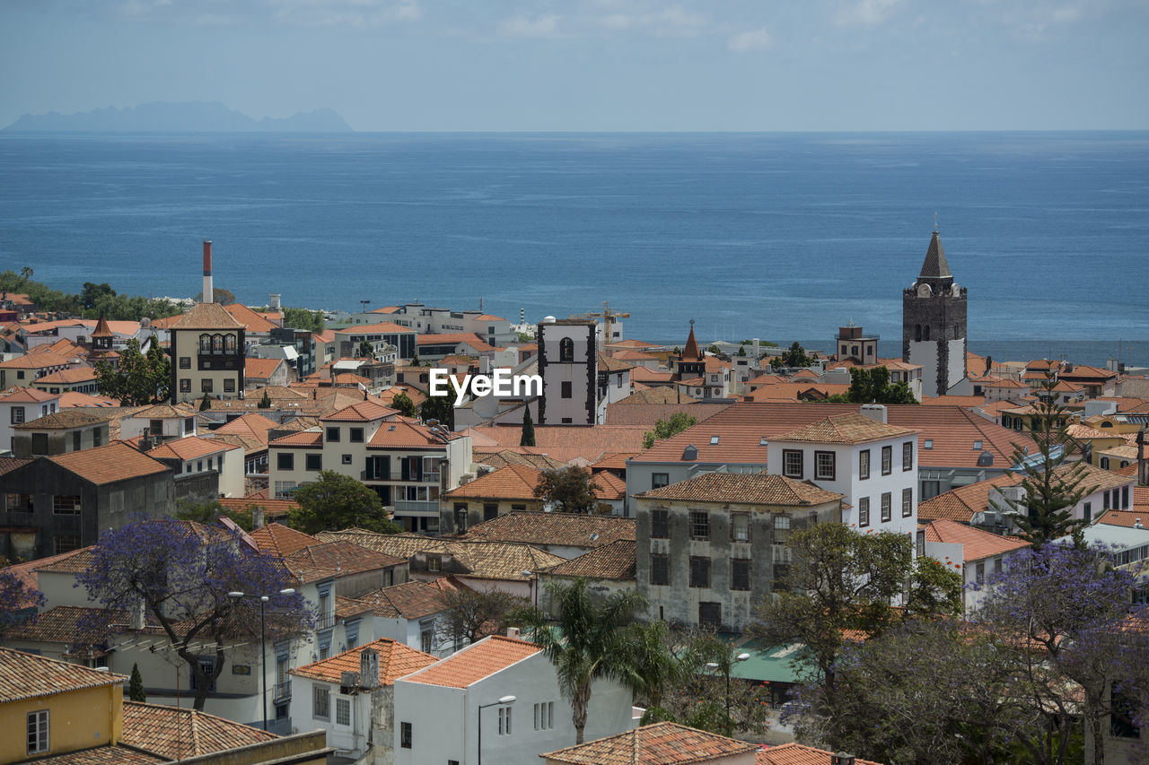 HIGH ANGLE SHOT OF TOWNSCAPE BY SEA AGAINST SKY