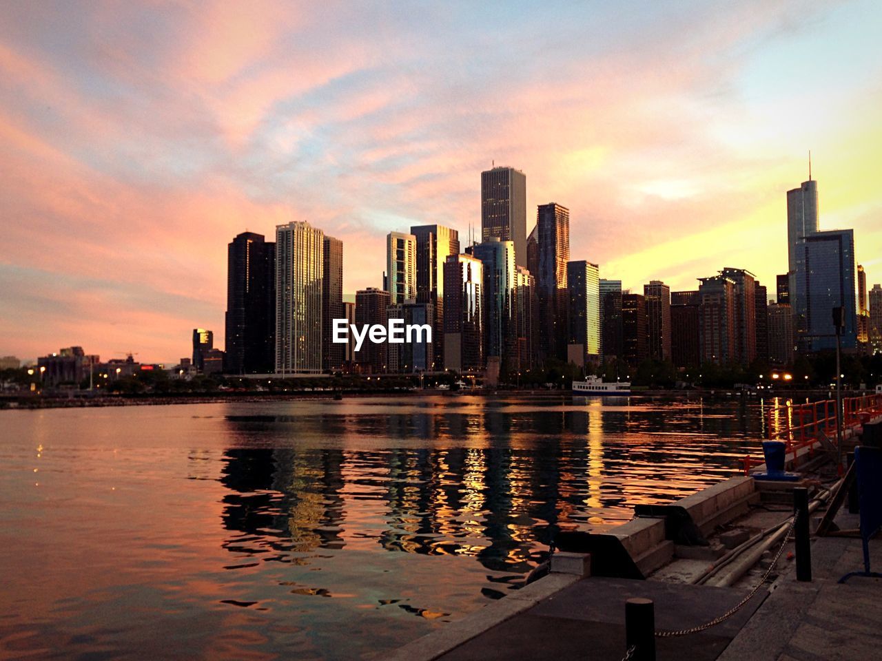 River and buildings against sky at sunset