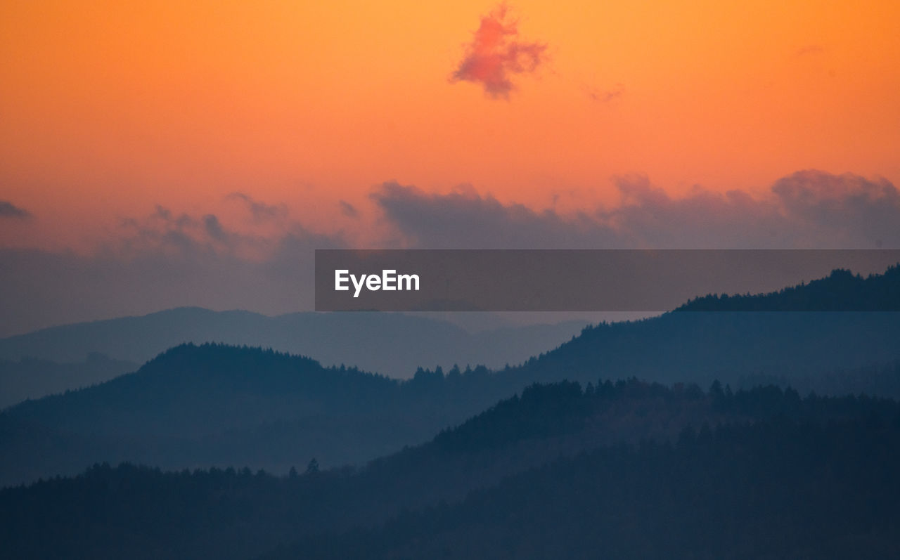 Scenic view of silhouette mountains against orange sky