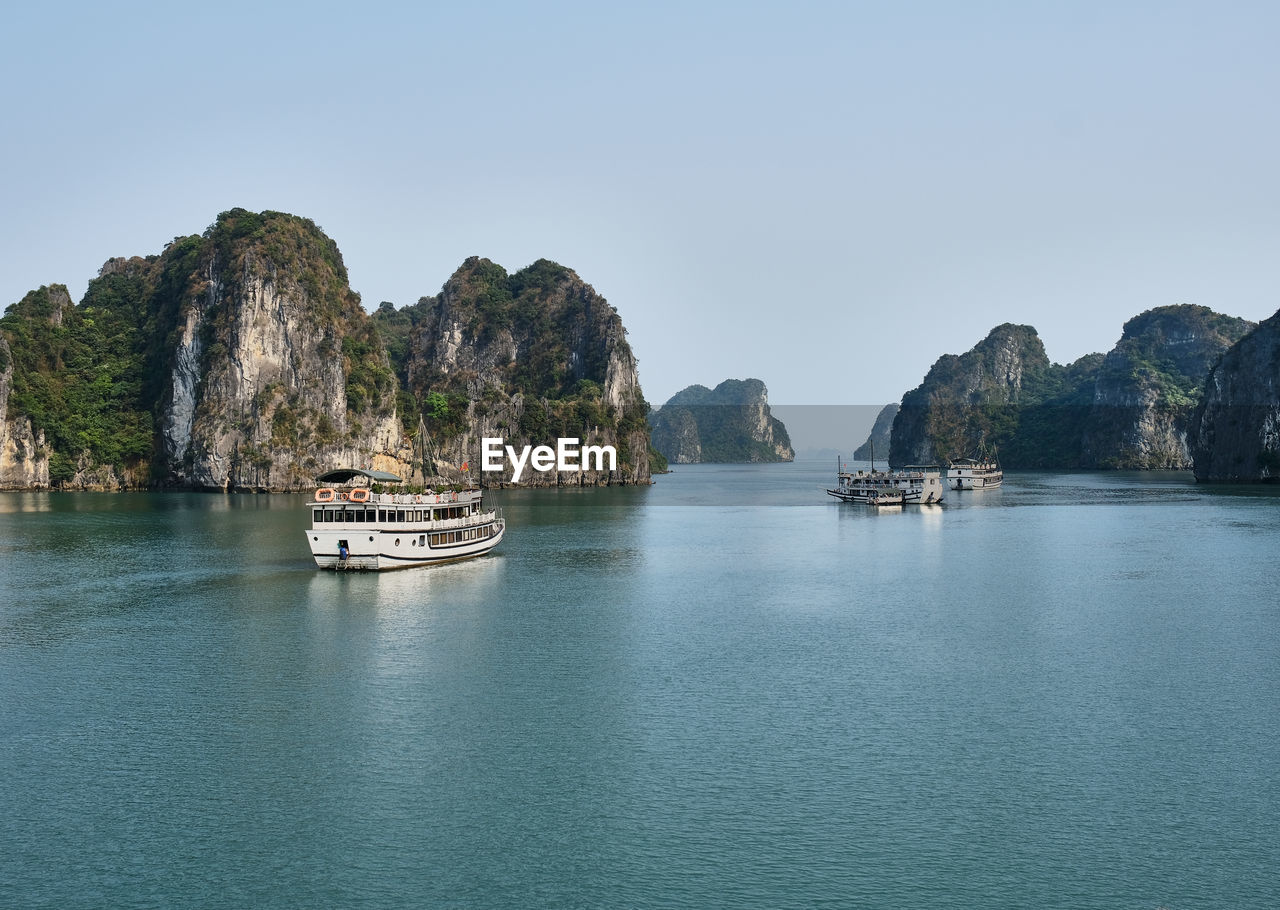 Boats sailing in sea against clear sky