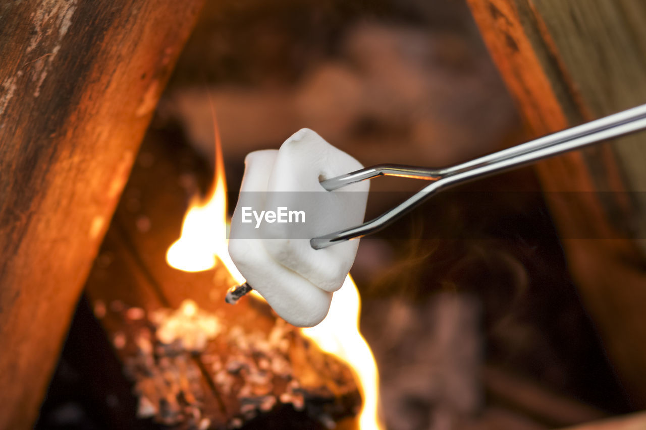 Close-up of marshmallow in skewer over campfire