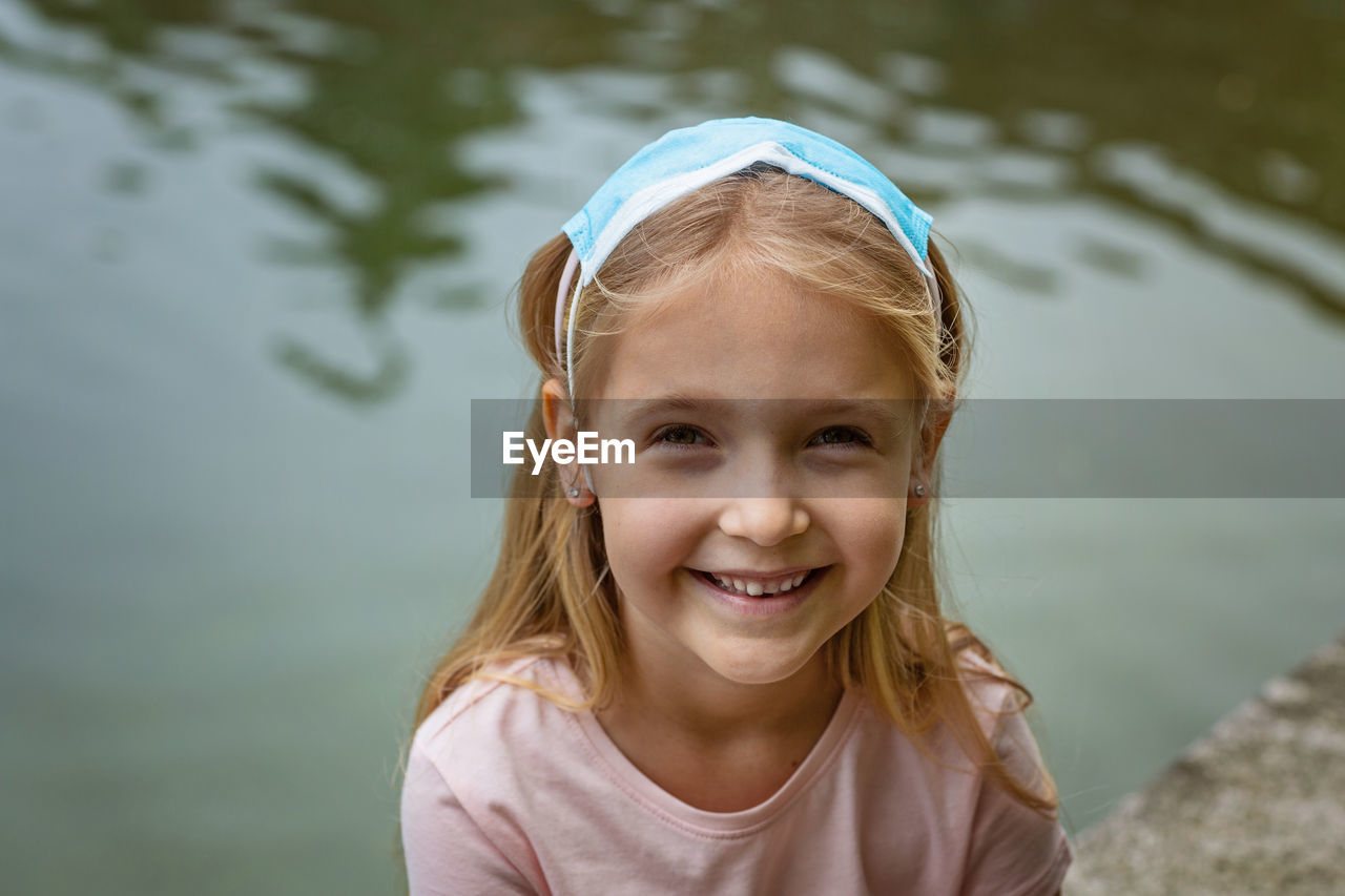 Happy little girl takes off protective medical mask from face outdoors. victory over coronavirus