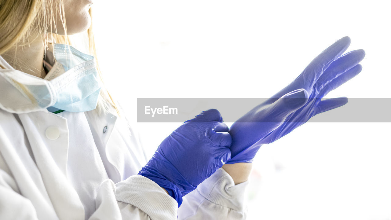 Medicine and surgery theme: female nurse putting on protective blue gloves