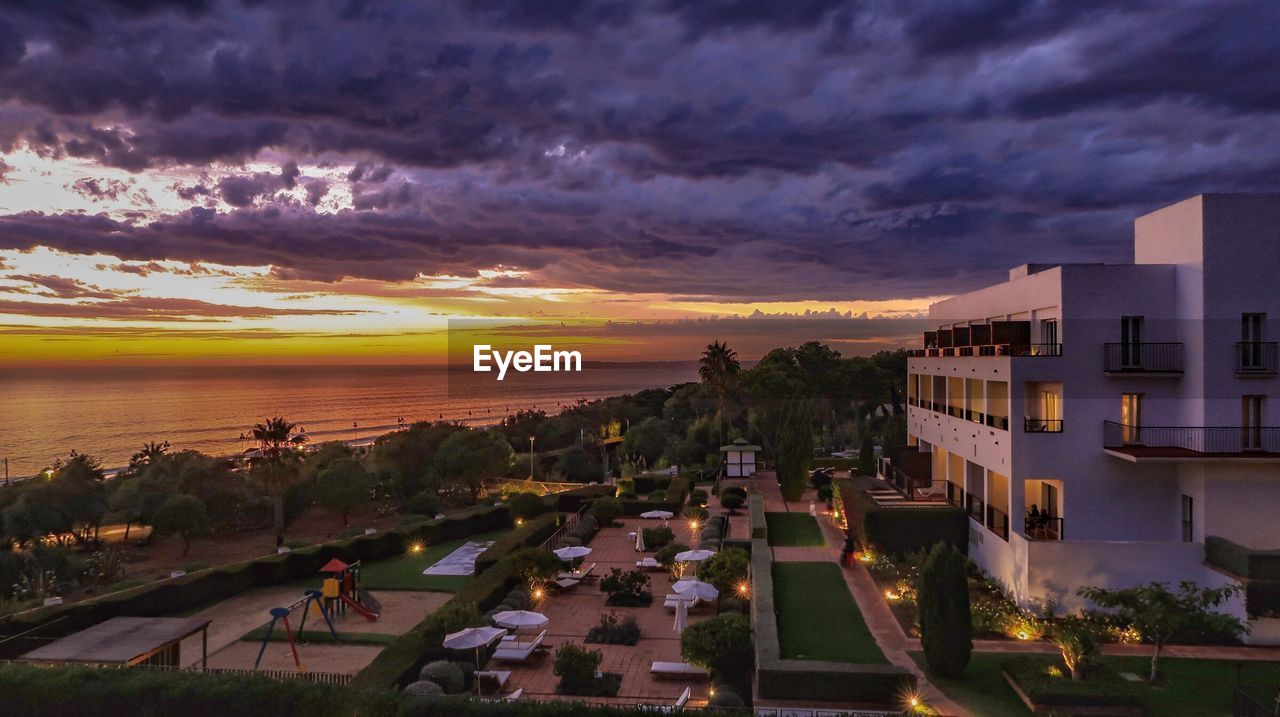 HIGH ANGLE VIEW OF BUILDINGS BY SEA AGAINST DRAMATIC SKY