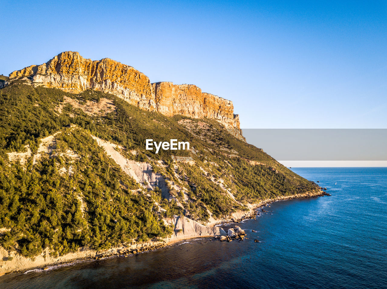 Scenic view of sea and mountains against clear blue sky