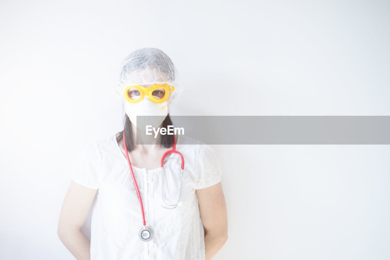 Portrait of teenage girl wearing sunglasses standing against white background