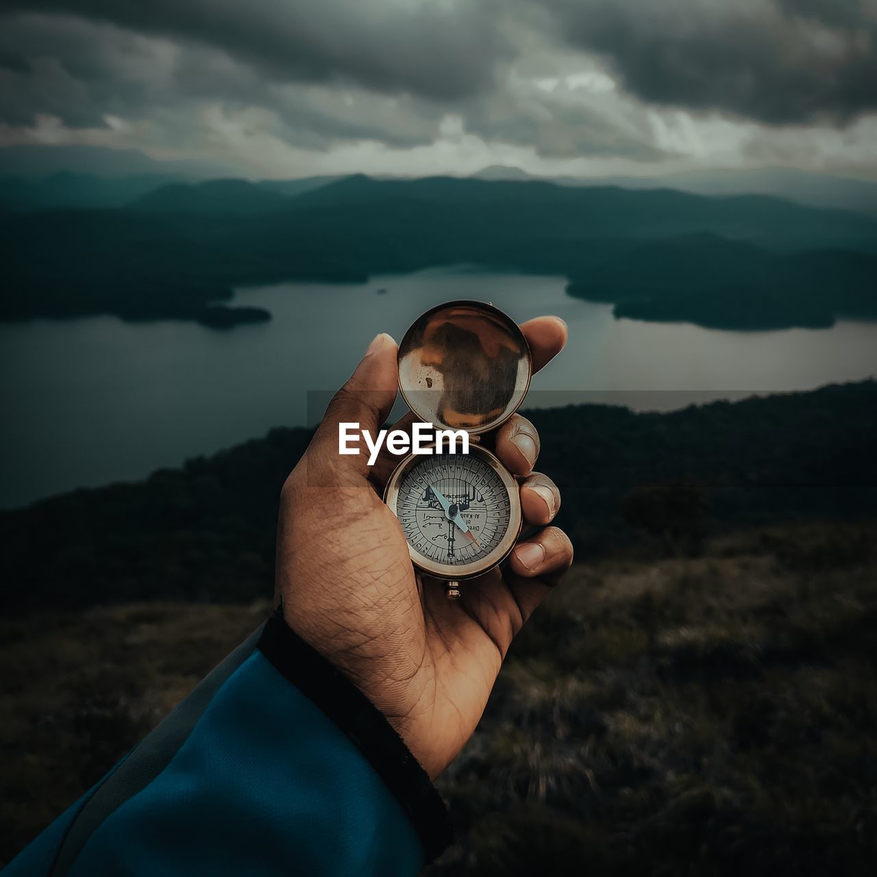 Midsection of person holding compass against mountain