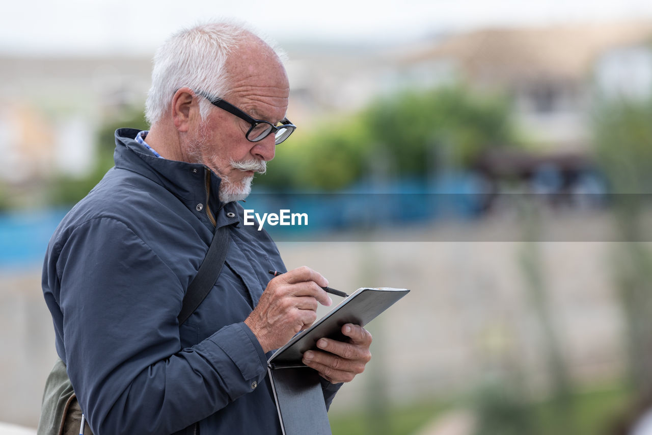 SIDE VIEW OF MAN USING SMART PHONE