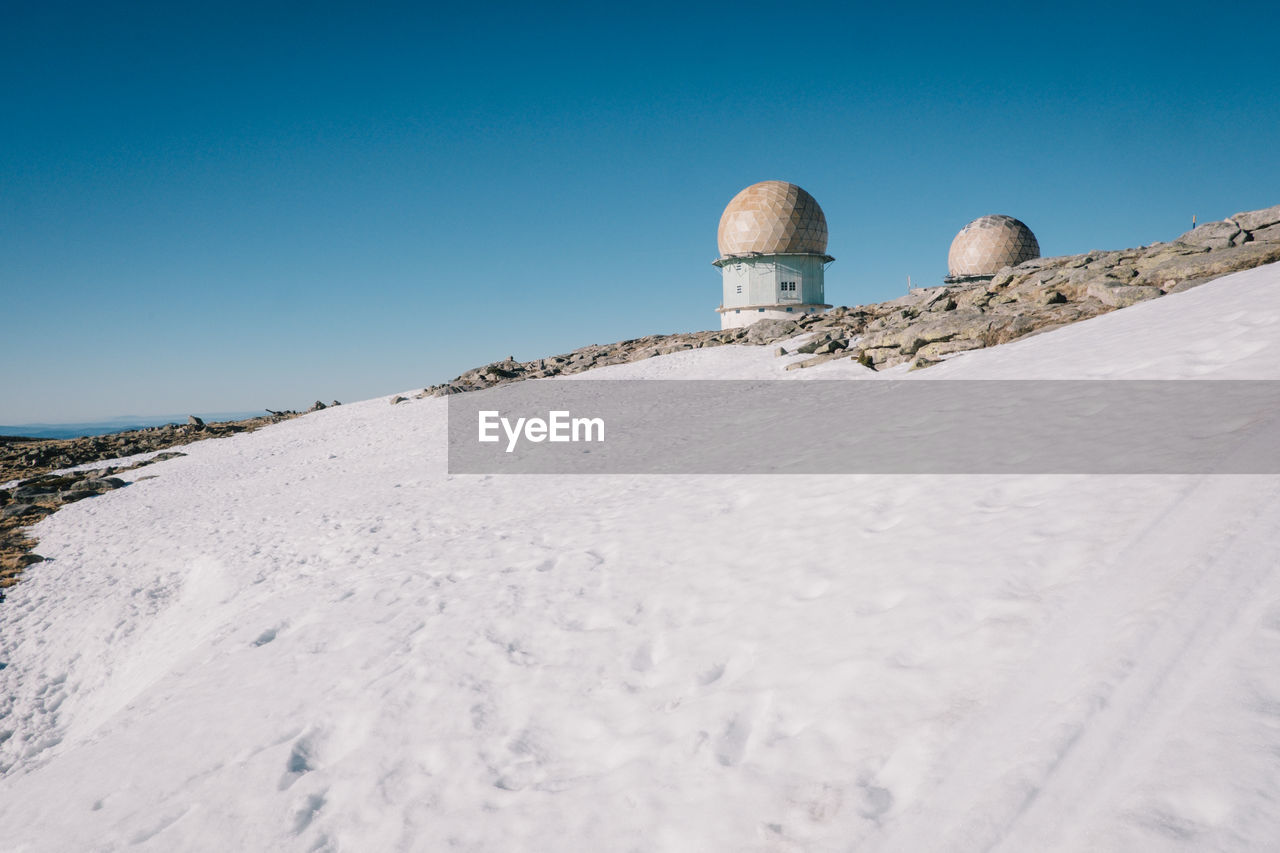 Low angle view of built structure in snow against sky