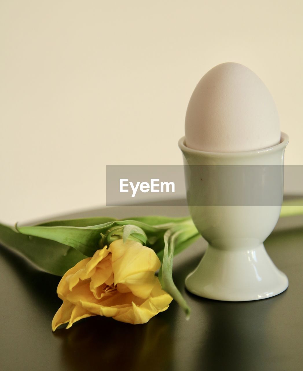 Close-up of yellow tulip and egg in eggcup on a table