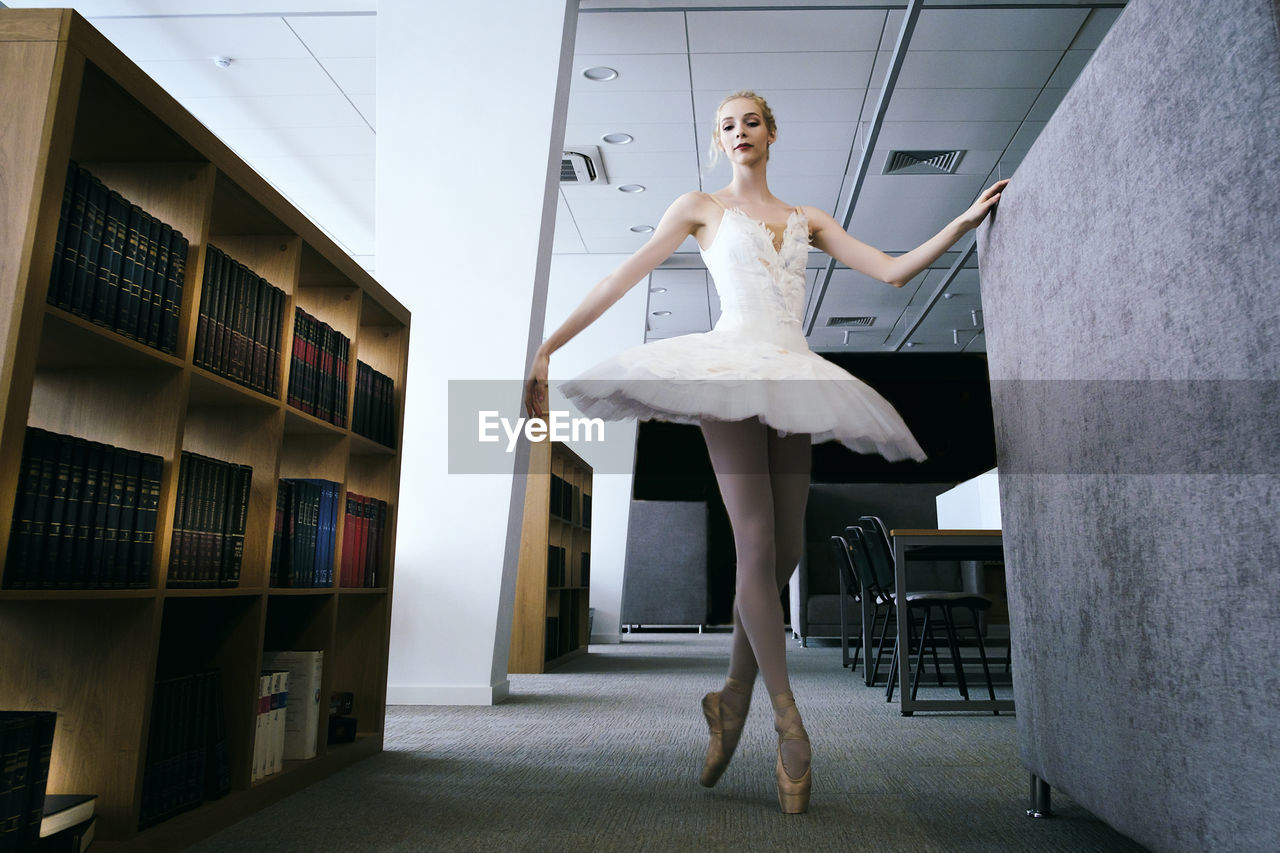 A charming ballerina went to the library to choose a new book during a break