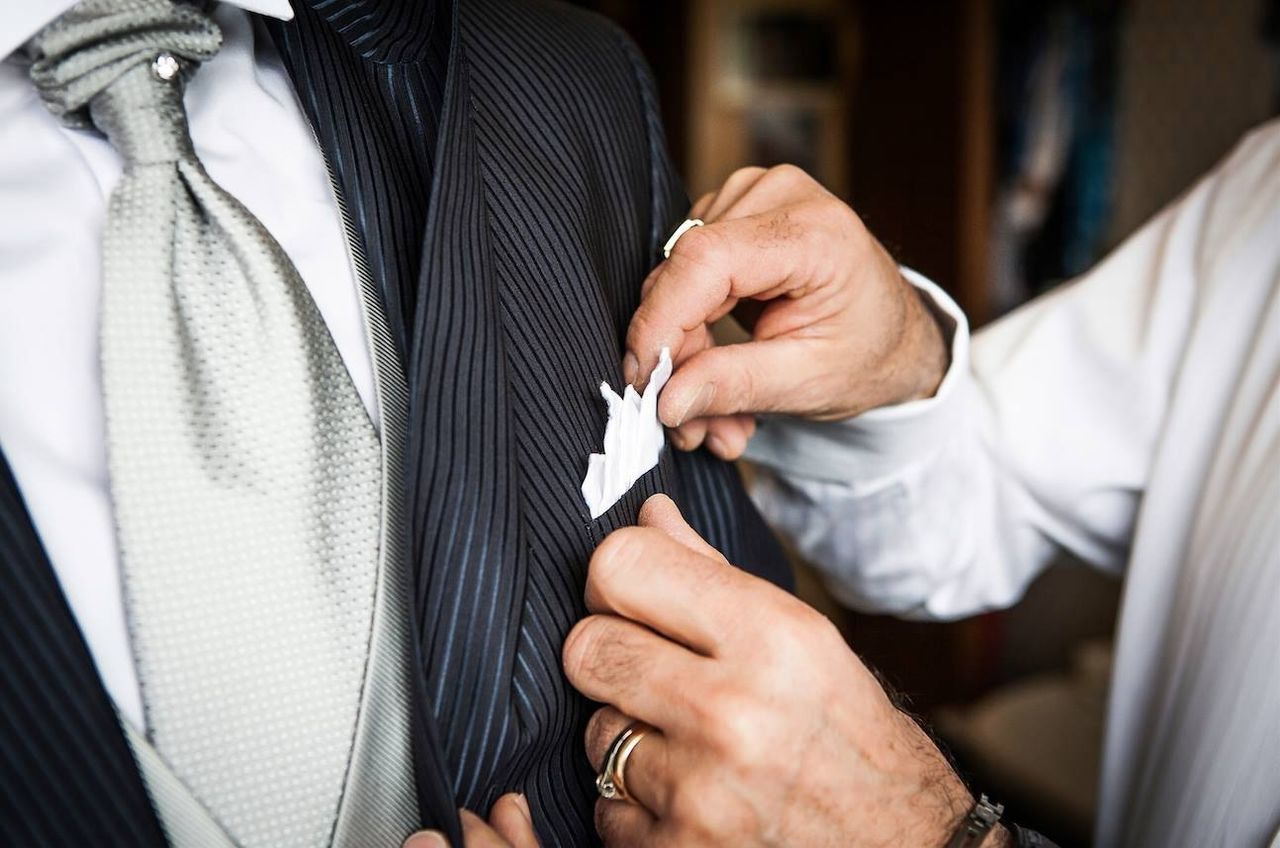 Cropped hand of man adjusting handkerchief of friend