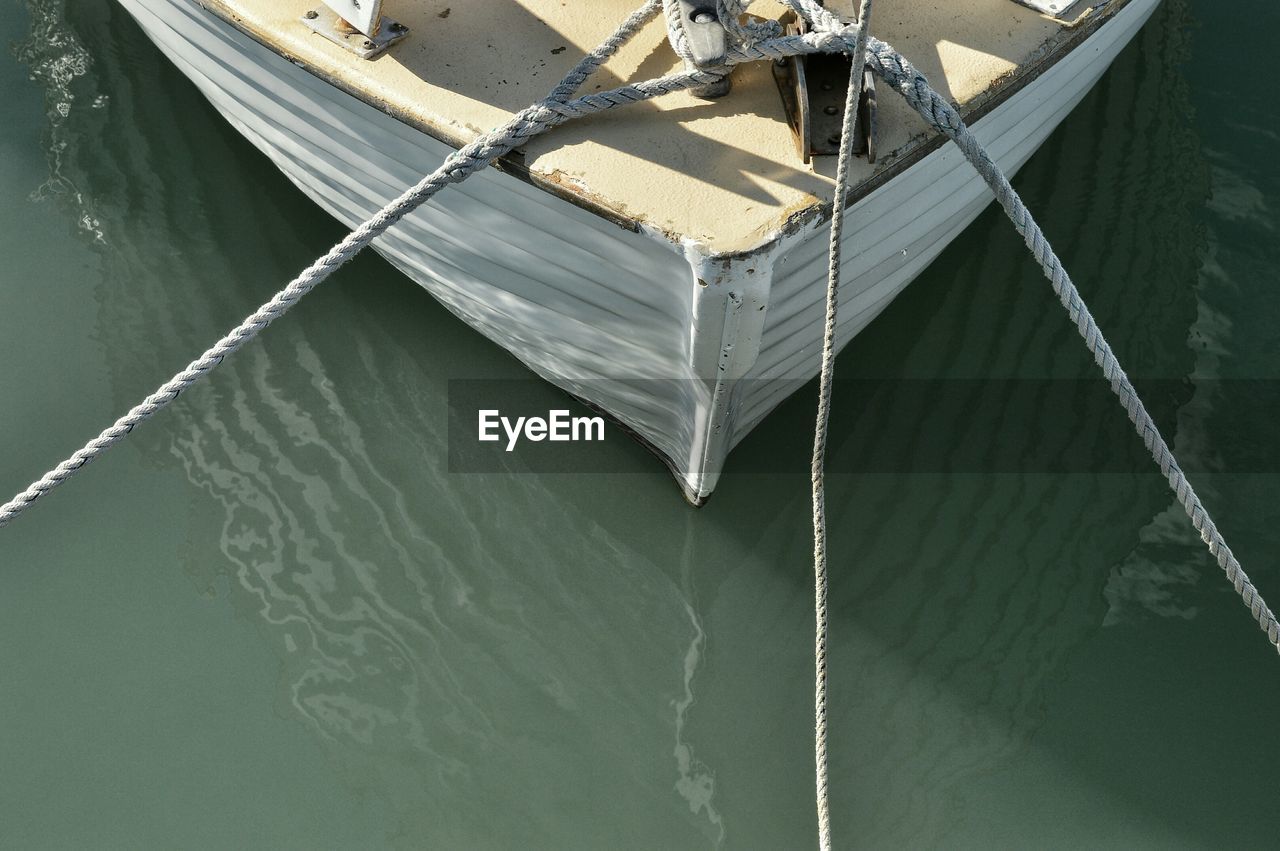 Cropped image of boat on water tied by rope