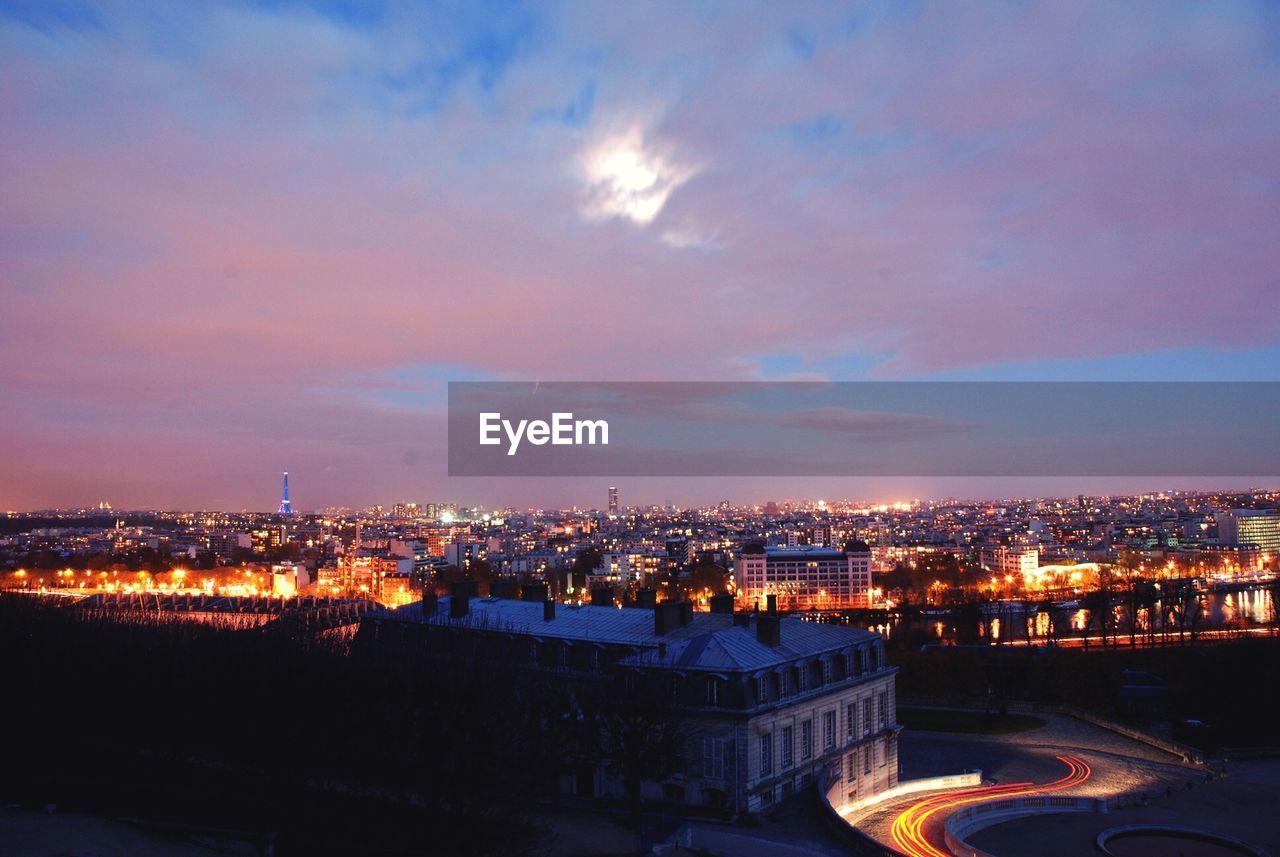 Illuminated cityscape against sky at dusk