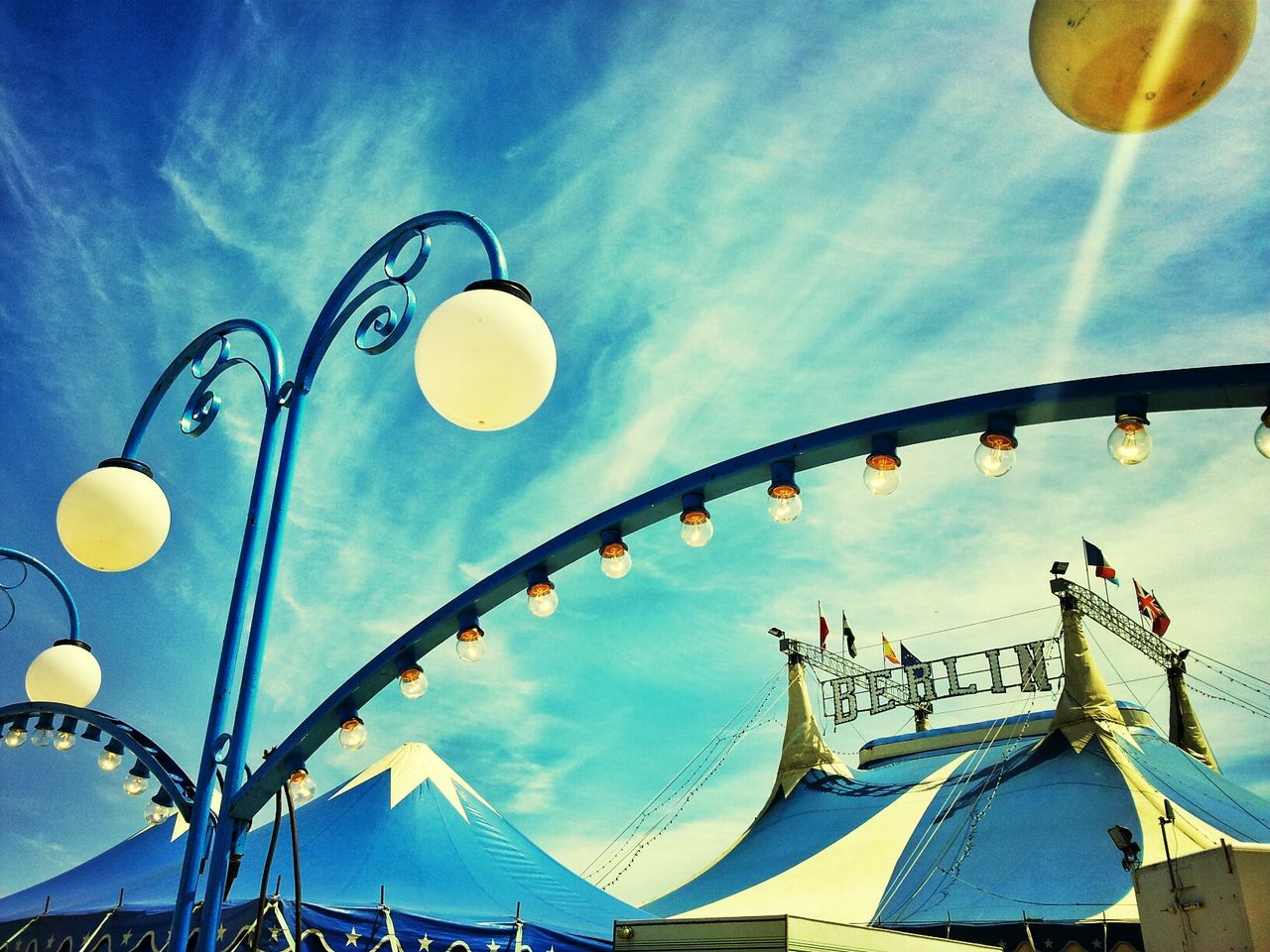 Low angle view of light bulbs against sky outside circus