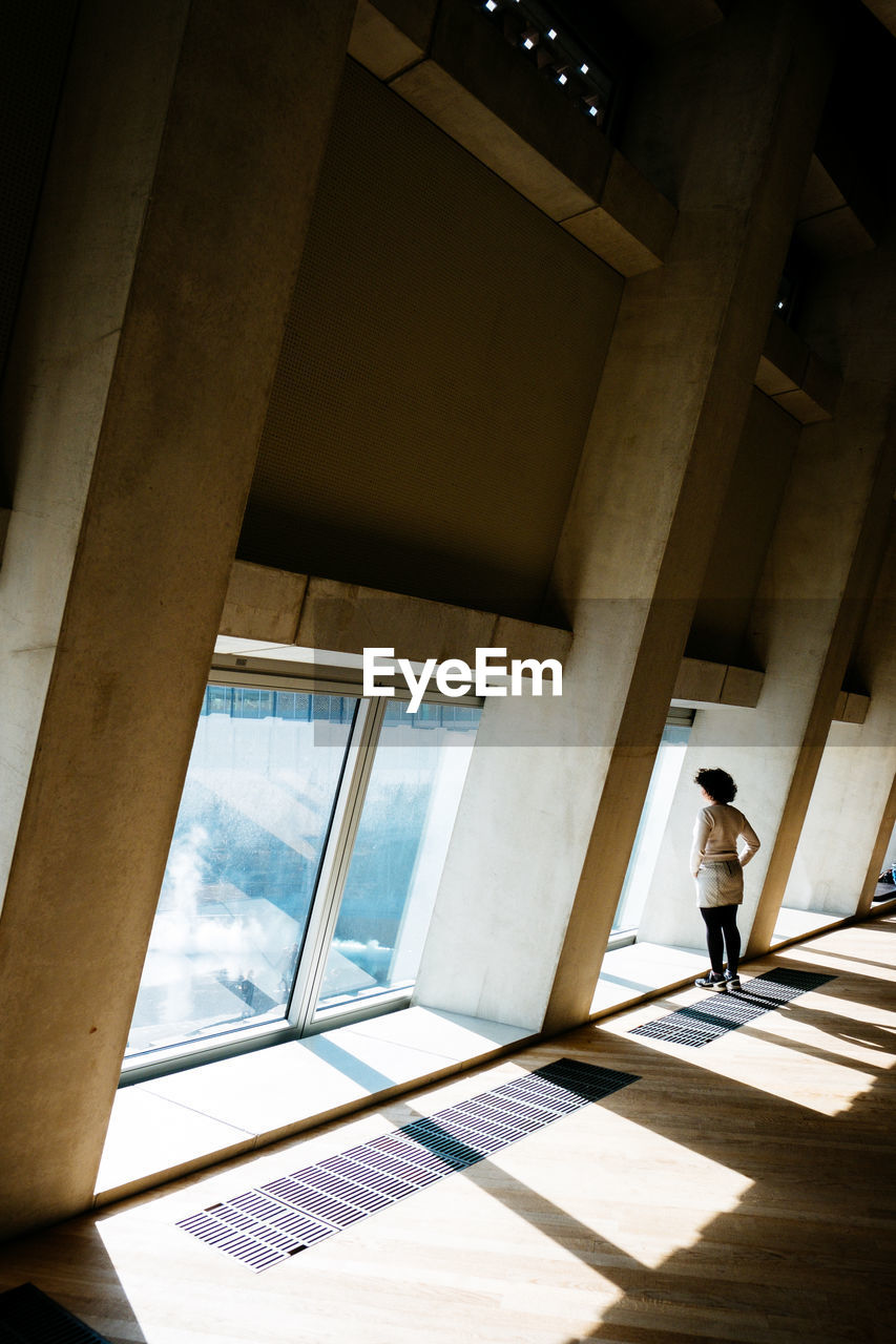 WOMAN STANDING BY WINDOW IN OFFICE