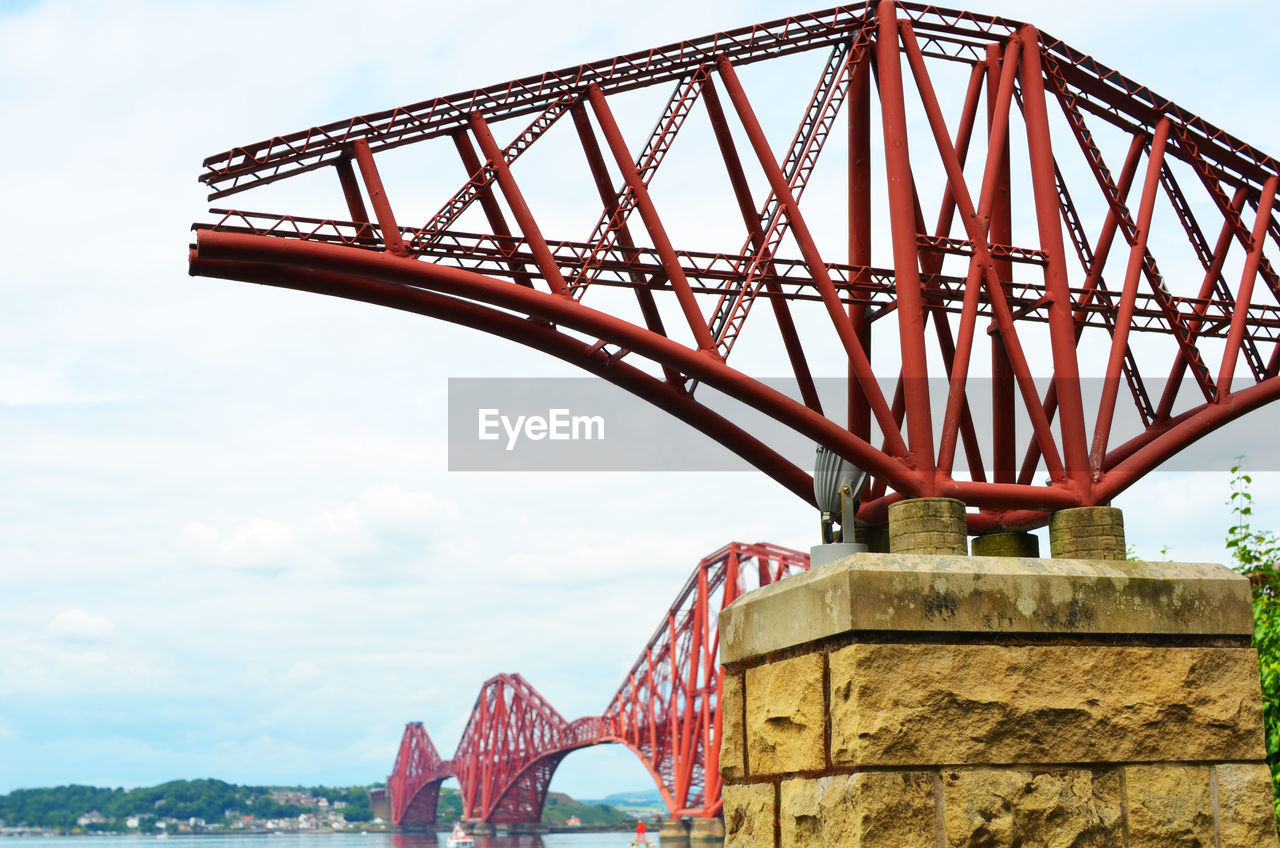 Metal structure by forth bridge against sky
