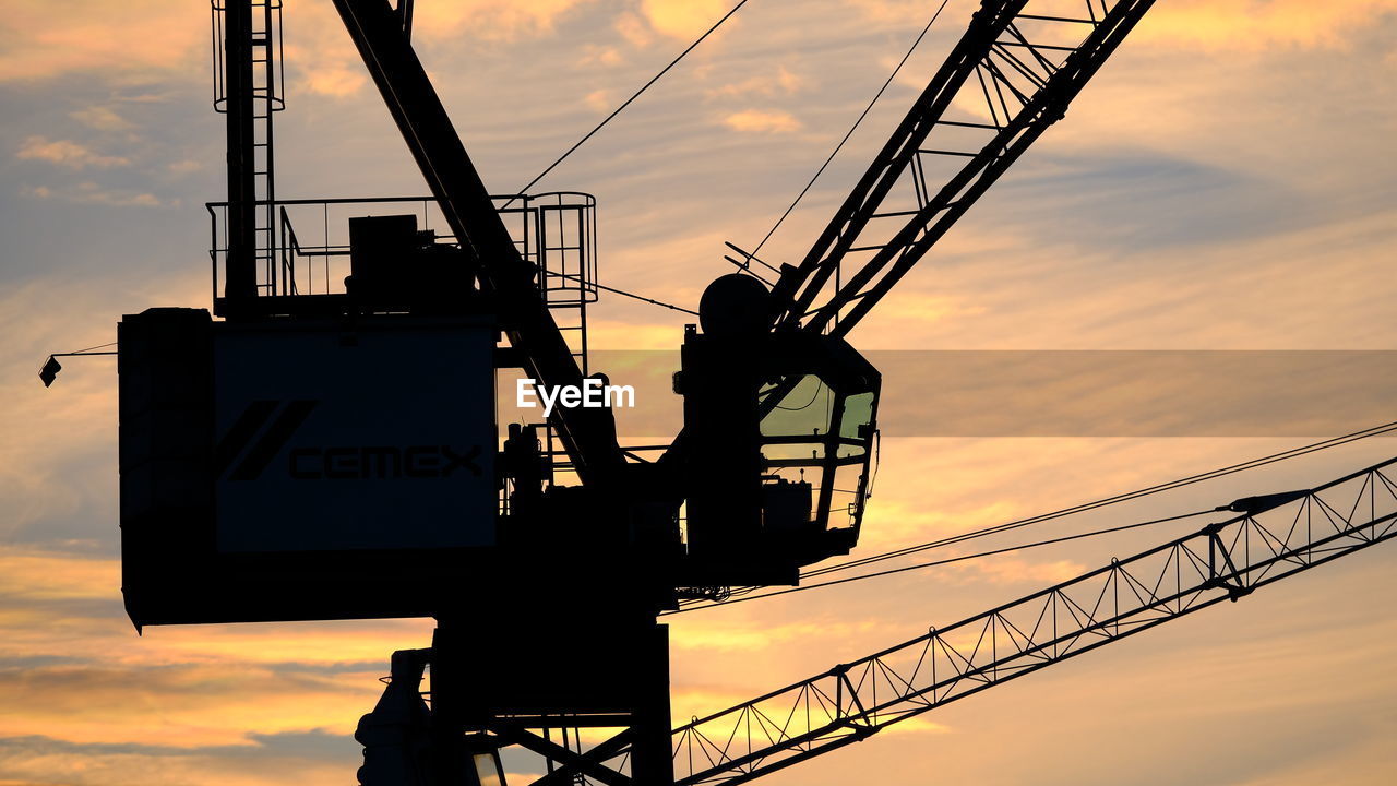 sunset, sky, real people, silhouette, occupation, working, orange color, low angle view, cloud - sky, sign, men, nature, outdoors, one person, architecture, construction industry, built structure, industry, machinery