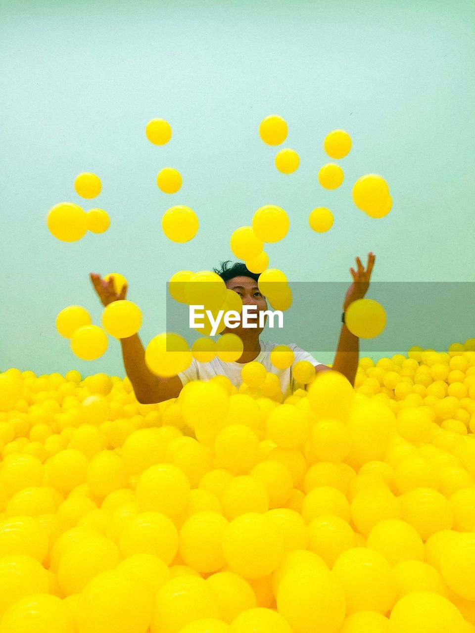 Man playing in ball pool against wall