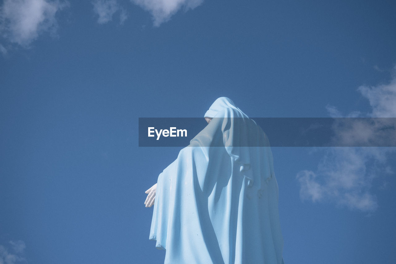 Low angle view of virgin mary statue against blue sky