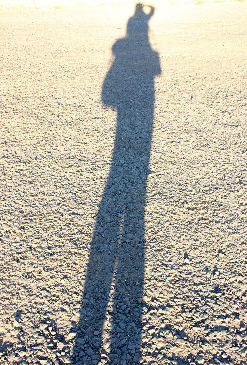 High angle view of person shadow on gravel