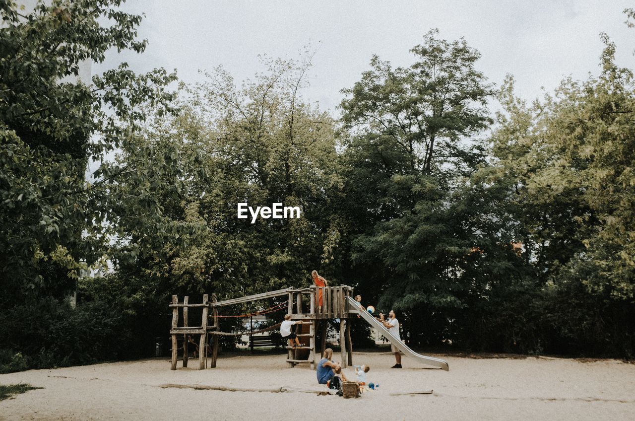 People playing on playground against trees