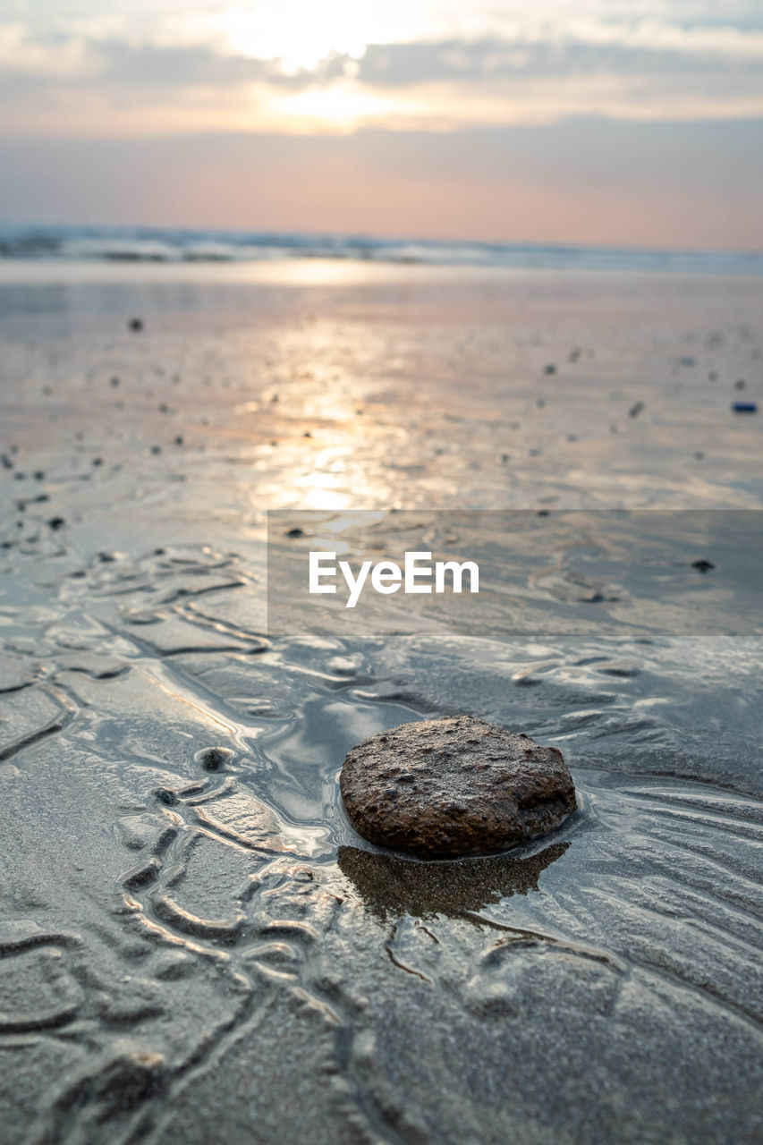 Rocks on beach against sky during sunset