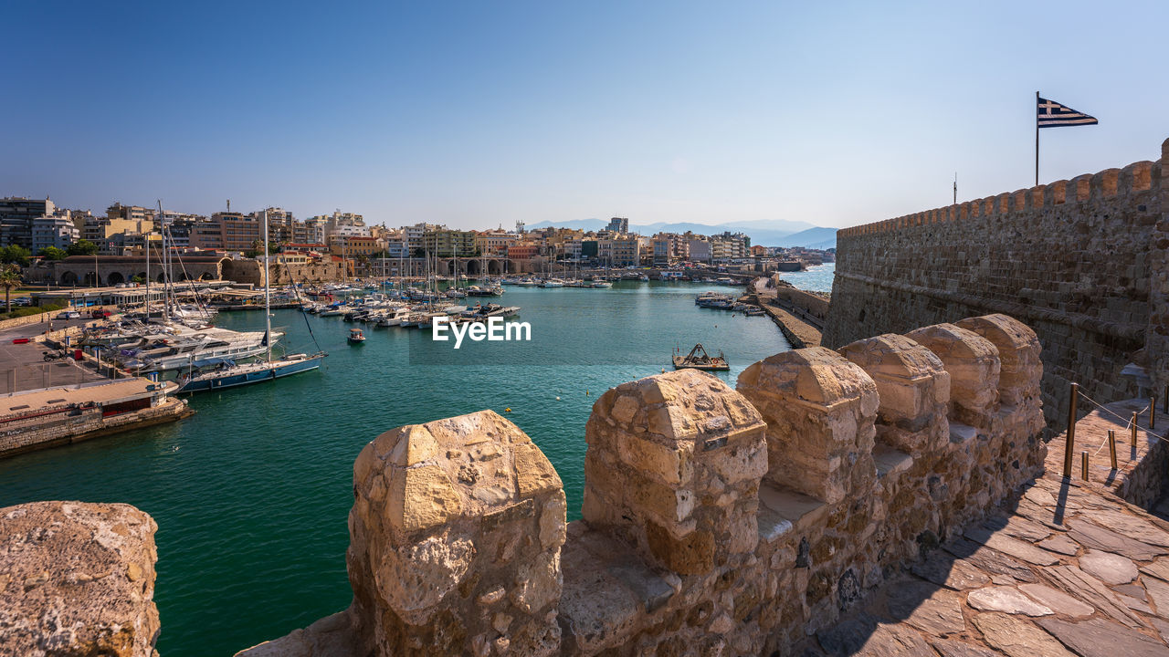 Boats in harbour against clear sky