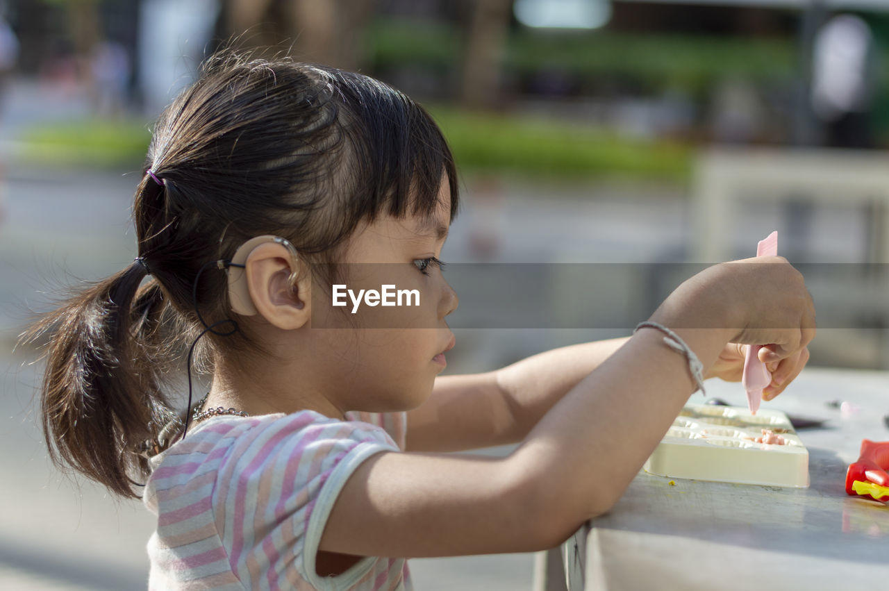 Close-up of cute girl playing with childs play clay at table outdoors