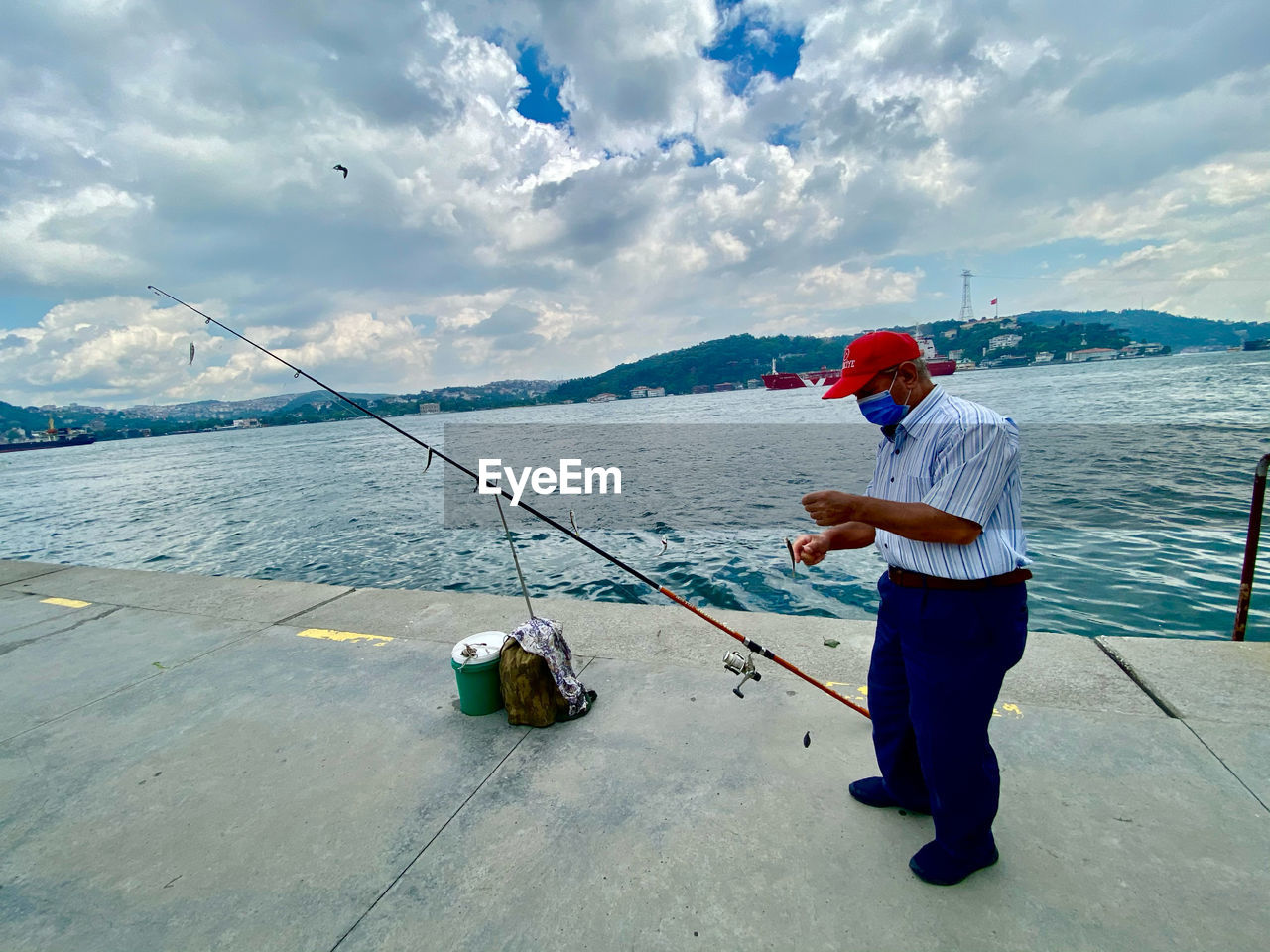 Man fishing in sea against sky