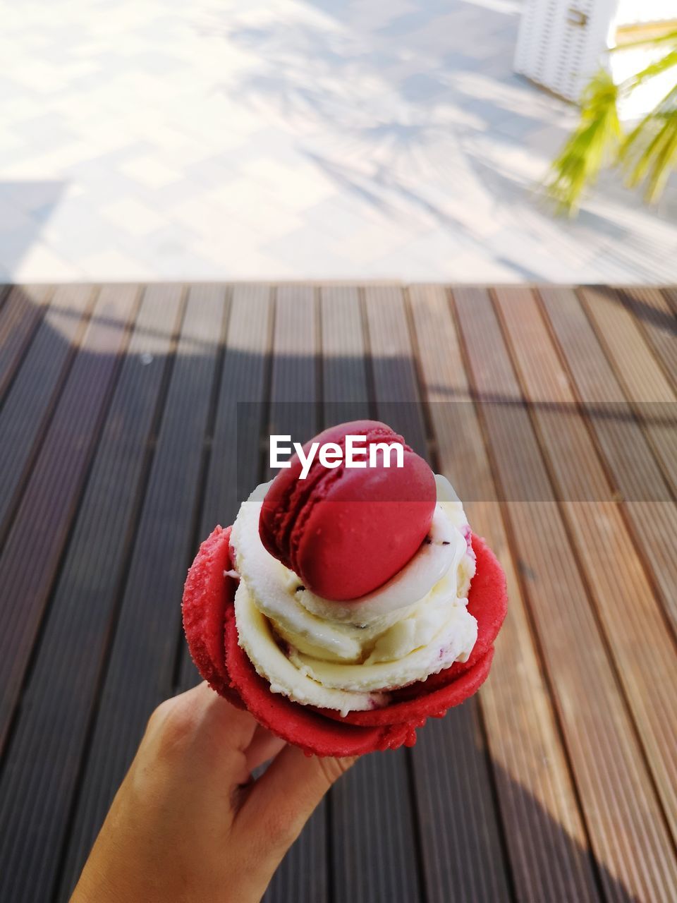 Cropped image of person holding ice cream over boardwalk