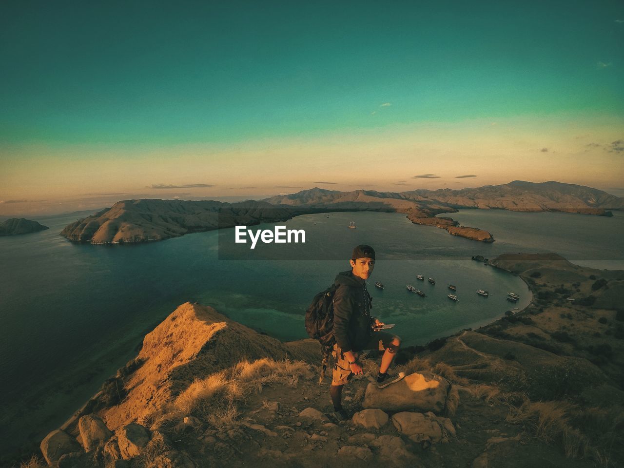 Portrait of man standing on mountain against sea during sunset