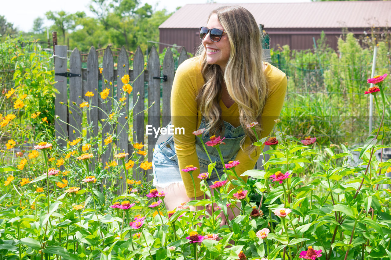 Smiling young woman standing by plants