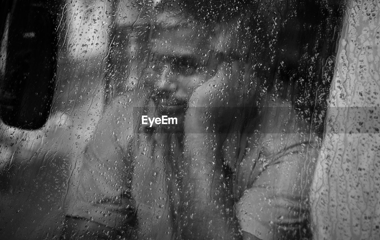 Man seen through wet window in rainy season